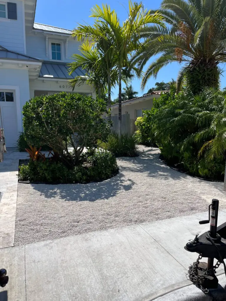 Front yard Fort Lauderdale landscaping, featuring a white house, palm trees, and tropical plants.